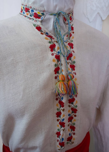 Vyshyvanka - Ukrainian national outfit. Embroidered shirt, charm, talisman,  handmade cross stitch, floral ornament, Ukrainian culture. Man shirt, blur and selective focus - Photo, Image