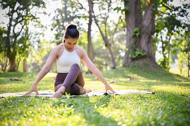 Портрет жінки, яка займається позуванням йоги і розтягує її тіло в парку вранці, здоровий спосіб життя і концепція діяльності
 - Фото, зображення