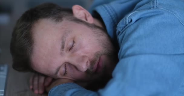 白人は疲れたITの男を寝かしつけて、オフィスの職場でカメラを見てまっすぐに目を覚ます。仕事で燃え尽きたストレスの多い仕事に疲れてデスクで寝ている男は、エネルギーを欠いている。4kビデオ - 映像、動画