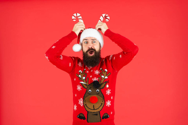 surprised mature guy in santa hat and sweater on red background, new year. - Fotografie, Obrázek