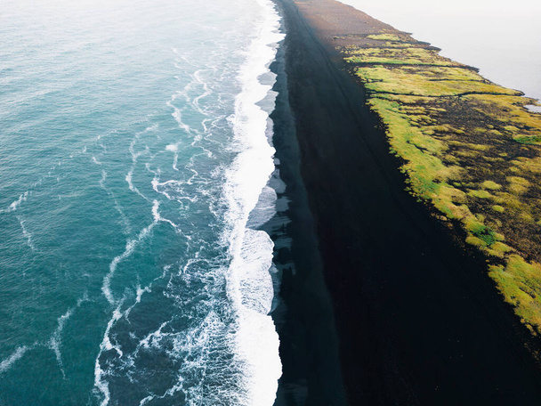 Playa de arena negra volcánica con vistas a Reynisdrangar. Olas rompiendo en la playa de arena negra. Vik, Islandia. Foto de alta calidad - Foto, Imagen