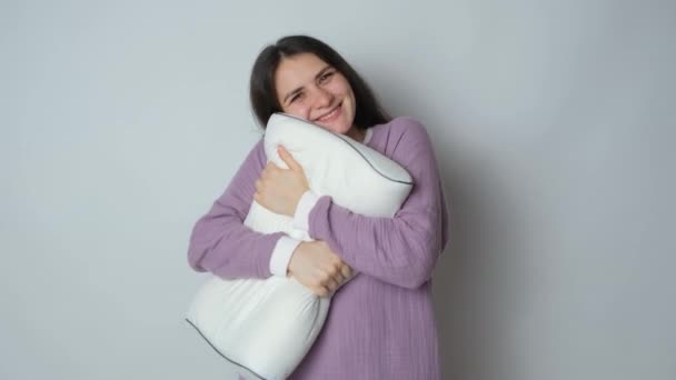 Beautiful brunette woman in muslin purple pajamas sleeping clothes hugs the orthopedic pillow - Footage, Video