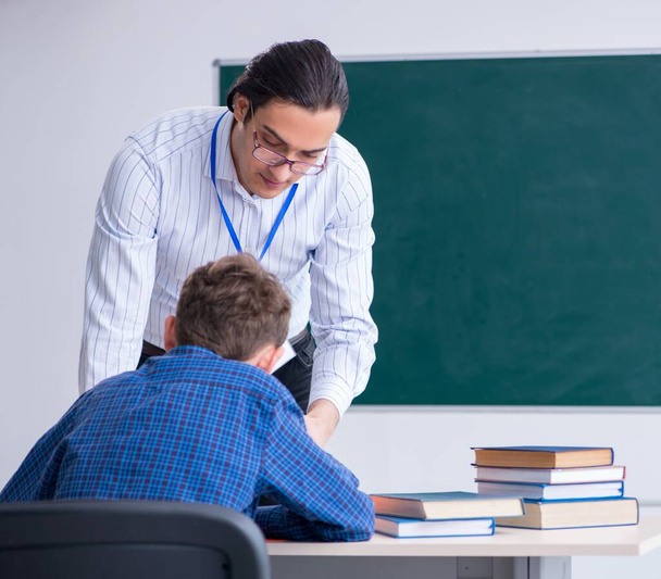 Молодой учитель и мальчик в классе - Фото, изображение