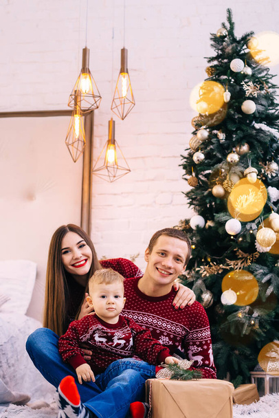famille heureuse regardant dans la caméra sur le fond de l'arbre de Noël. look familial. - Photo, image