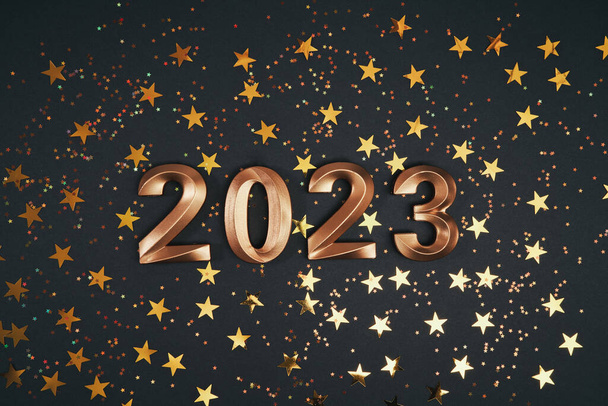 Números dorados del año 2023. Guirnalda festiva brillante con bokeh sobre fondo oscuro. Feliz Año Nuevo tarjeta de felicitación. Tarjeta de felicitación con estrellas - Foto, Imagen
