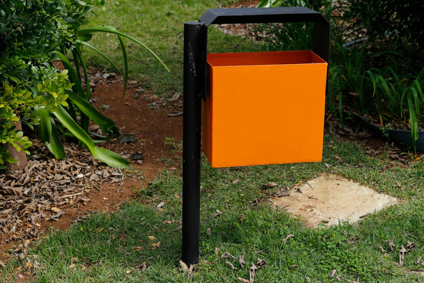 orange metal trash can in green and gardened public area - garbage collection - Fotó, kép