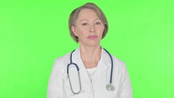 Denying Senior Female Doctor Shaking Head to Stop on Green Background - Fotografie, Obrázek