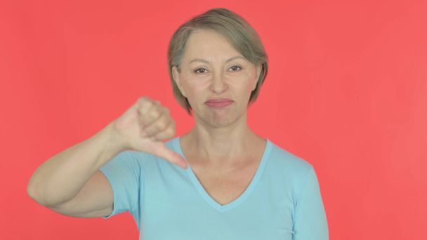 Thumbs Down by Senior Old Woman on Red Background - Photo, Image