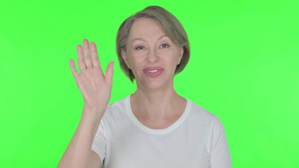 Senior Old Woman Waving Hand to Say Hello on Green Background - Photo, Image