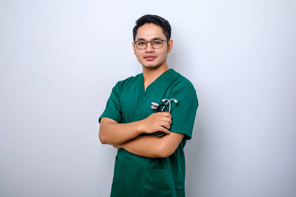 Professional good-looking asian doctor, medical worker in glasses and scrubs, cross arms and smiling, isolated over white background - Photo, Image
