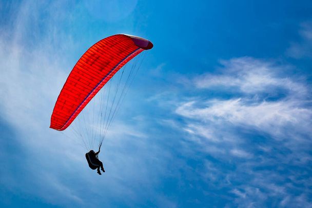 Bir paraglider mavi gökyüzünde uçuyor. Güneşli bir günde paraşütle atlamak. - Fotoğraf, Görsel