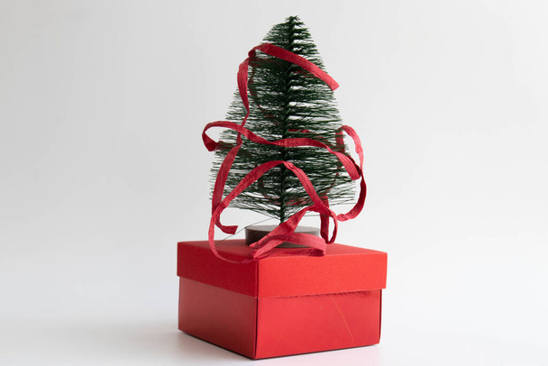 Χριστουγεννιάτικο Δέντρο για Διακόσμηση σε κόκκινο κουτί δώρου, τυλιγμένο με κόκκινη χάρτινη κορδέλα , - Φωτογραφία, εικόνα