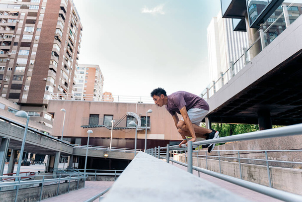 Focused young man practicing parkour tricks in the city and having fun. - Fotó, kép