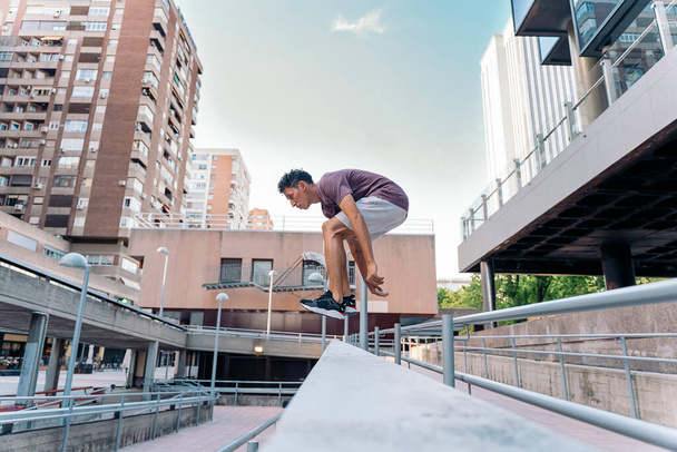 Concentrated young man practicing parkour tricks in the city and having fun. - 写真・画像