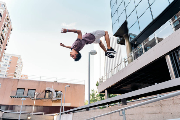 Talented young man practicing parkour tricks in the city and having fun. - Foto, imagen