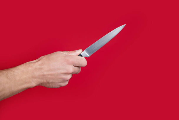 sharp cooking knife in male hand on red background. - Foto, Bild