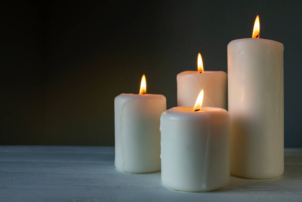 Large burning candles on a dark background. - Foto, afbeelding