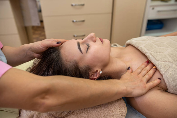 красива молода дівчина з темним волоссям робить масаж голови в масажному салоні. Концепція масажу голови
 - Фото, зображення
