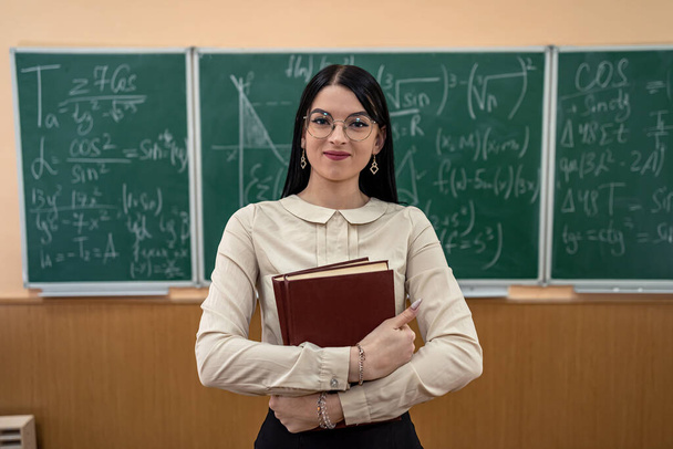retrato de una joven maestra contra pizarra con fórmula matemática en el aula. concepto de educación - Foto, Imagen