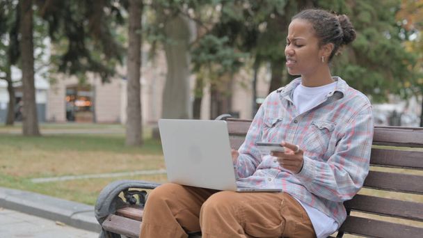 Jovem mulher africana tendo falha de pagamento on-line enquanto sentado ao ar livre no banco - Foto, Imagem