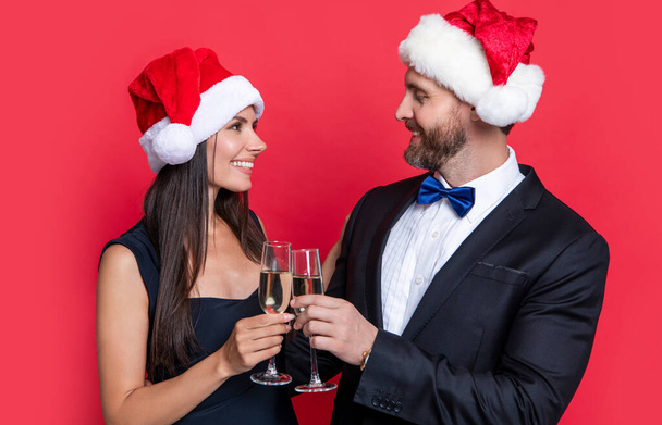 celebrate xmas party with happy couple. merry xmas to couple in studio. couple celebrate xmas. lets celebrate holiday. xmas couple celebrate with champagne isolated on red background. - Photo, Image