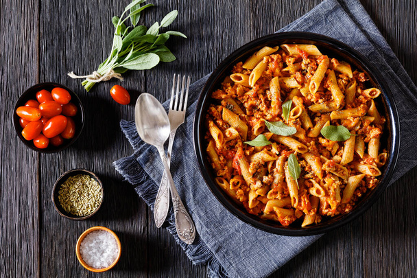 Whole wheat pasta bake with ground beef and melted red cheddar cheese on black  baking dish on dark wood table, landscape view from above, flat lay - Foto, Imagen