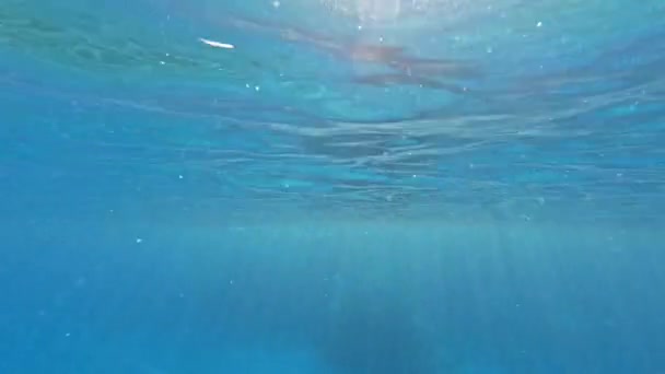 Луч солнца прорывается сквозь прозрачный голубой столб воды, освещая все вокруг, небольшие волны на поверхности воды - Кадры, видео