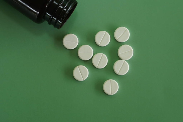 pílulas com recipiente contra fundo verde - Foto, Imagem