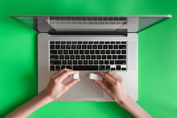 現代のラップトップで働く女性の手。緑の背景にオフィスのデスクトップ。女性の手は、ラップトップのキーボード上のテキストを入力します。 - 写真・画像