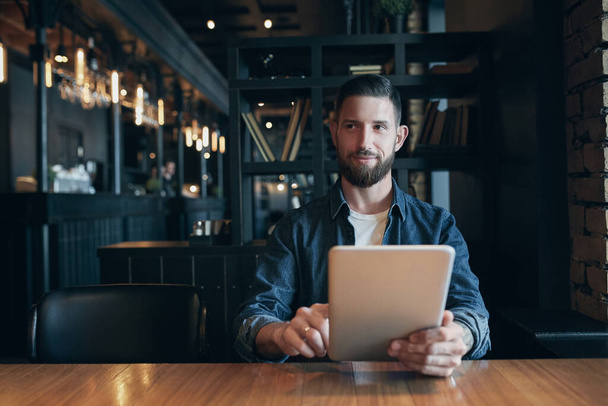 Современный хипстерский бизнесмен пьет кофе в городском кафе во время обеда и работает над планшетом. Фрилансер
 - Фото, изображение