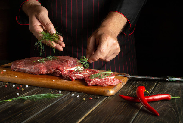 Lo chef mette foglie di aneto sulla carne prima di grigliare. Deliziosa ricetta di vitello per hotel. Piatto nazionale asiatico - Foto, immagini
