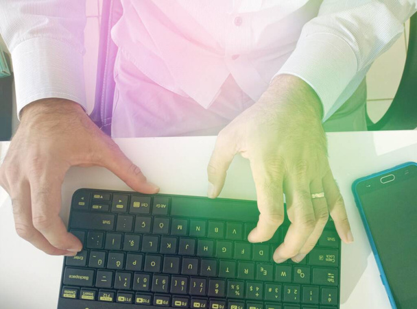 L'homme d'affaires travaille à l'ordinateur. Juste une image des mains et du clavier. Sous effet de lumière verte et jaune. - Photo, image