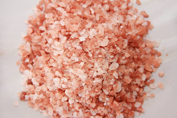 pequeños gránulos de sal rosada del Himalaya sobre un fondo de mármol gris - Foto, imagen