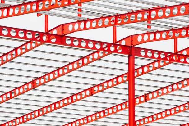 červená kastelovaný trám kovová střecha konstrukce velké průmyslové budovy na staveništi proti bílému oblačnému pozadí oblohy - Fotografie, Obrázek
