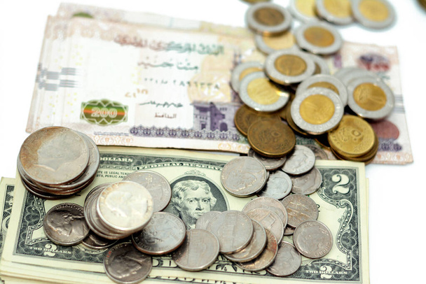 stapels Amerikaanse munten van 1 dollar, 50 cent, kwartjes, 10 cent en 1 cent en Egyptische munten van 1 EGP LE een pond en een half pond 50 piasters op een stapel Amerikaanse en Egyptische bankbiljetten - Foto, afbeelding