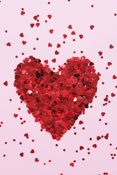 День святого Валентина. Сердце из блестящего красного маленького декоративного сердца на розовом фоне. Квартира лежала, место для смс. Праздничный минимальный состав. Вертикальное изображение. - Фото, изображение