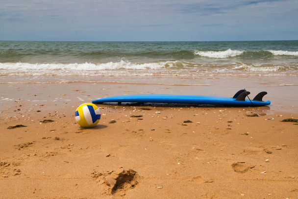Серфінг і волейбол на піску пляжу на березі. На задньому плані видно море. Концепція спорту на відкритому повітрі
. - Фото, зображення