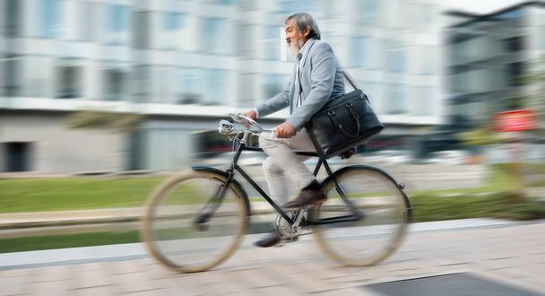 Bicikli, ingázás és elmosódott mozgás egy érett férfival, aki a városban biciklizik a reggeli munkalátogatásán. Út, utazás és kerékpár egy idősebb férfi alkalmazottal, aki a város egyik utcáján lovagol. - Fotó, kép