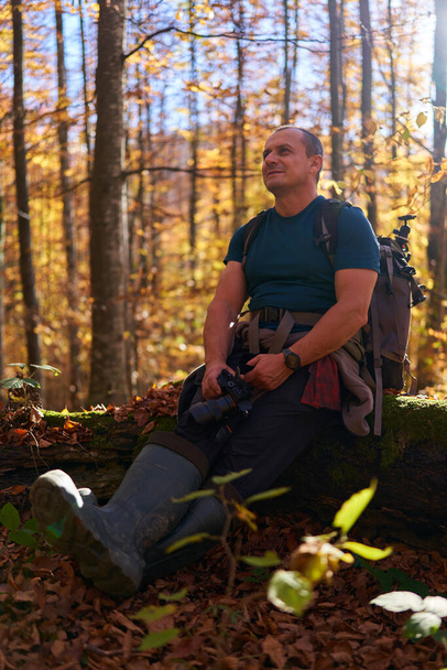 Nature photographer with heavy backpack hiking on a trail in the beech forest on mountain - Foto, afbeelding