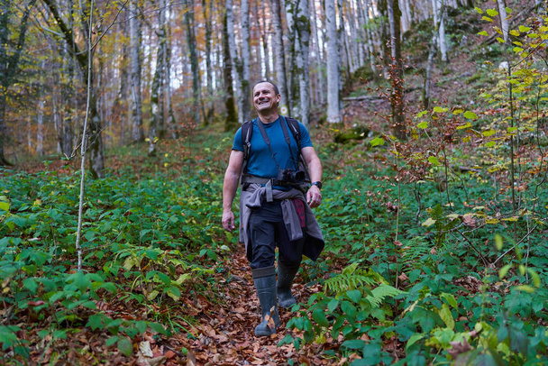 Nature photographer with heavy backpack hiking on a trail in the beech forest on mountain - Foto, imagen