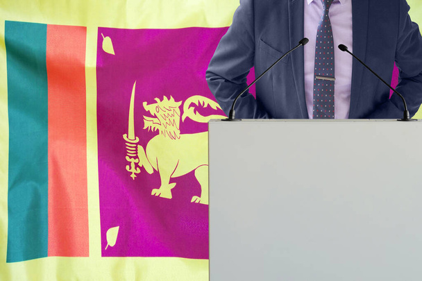 Tribune z mikrofonem i człowiekiem w garniturze na tle flagi Sri Lanki. Biznesmen i trybun na Sri Lance. Polityk na podium z mikrofonami w tle flaga Sri Lanki. Konferencja - Zdjęcie, obraz