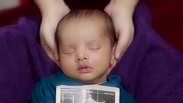 νεογέννητο μωρό κρατώντας αντίγραφο υπερήχων στο χέρι και κοιμάται στη μητέρα παλάμη σε περιτύλιγμα μωρού - Πλάνα, βίντεο