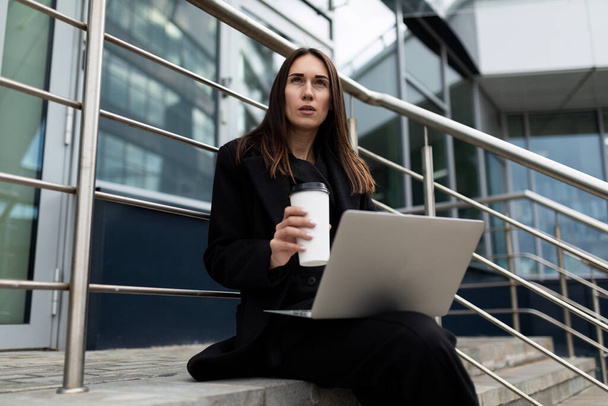 vrouw markt risico analist werken met laptop buiten kantoorgebouw. - Foto, afbeelding