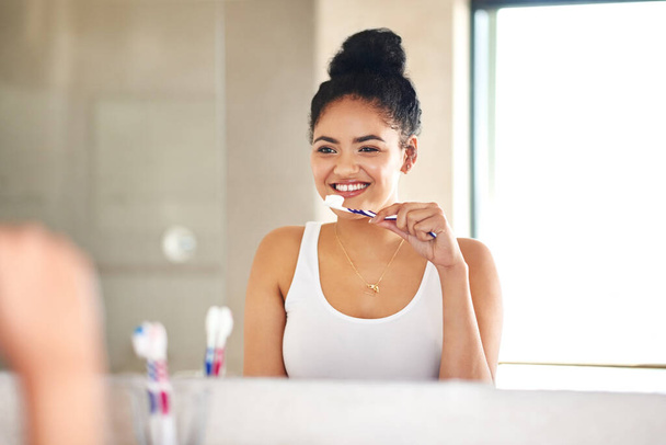 Güne parlak ve taze bir başlangıç yapıyoruz. Genç bir kadın banyoda dişlerini fırçalıyor. - Fotoğraf, Görsel
