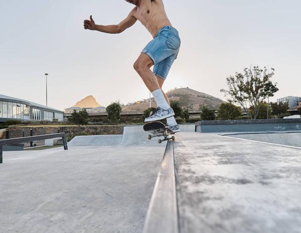 Skater, fitness en voeten van de mens skateboarden in een park voor plezier, avontuur en fitness. Sport, activiteit en training van een man die een plank gebruikt om buiten te schaatsen in een stad of stad voor lichaamsbeweging. - Foto, afbeelding
