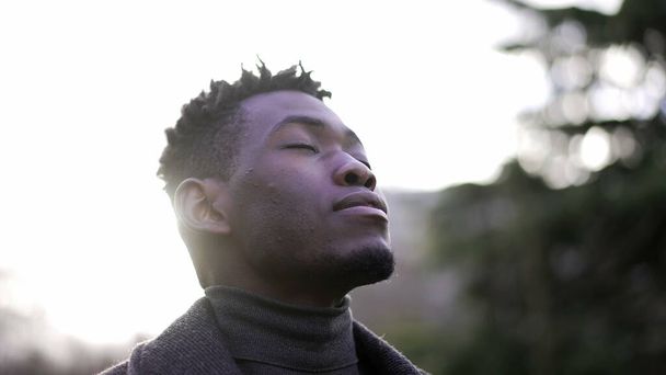 African man taking a deep breath outside at park. Close-up person meditating - Fotografie, Obrázek
