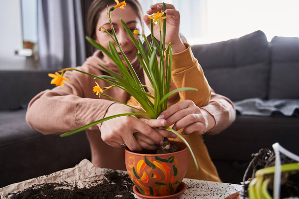Little boy with down syndrome looking with interest how his mother replacing flowers and helping to her at the living room. Family concept - Photo, image