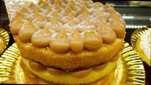 Layered vanilla cake with frosting and dulce de leche filling, in a Brazilian bakery showcase. - Footage, Video