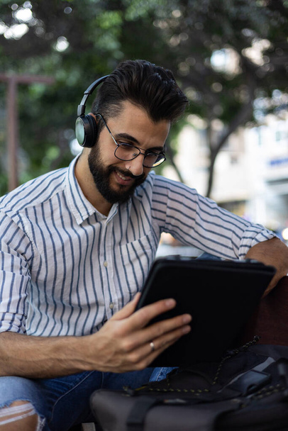 Portrait of young man with beard looking at his tablet smiling - Foto, Imagem