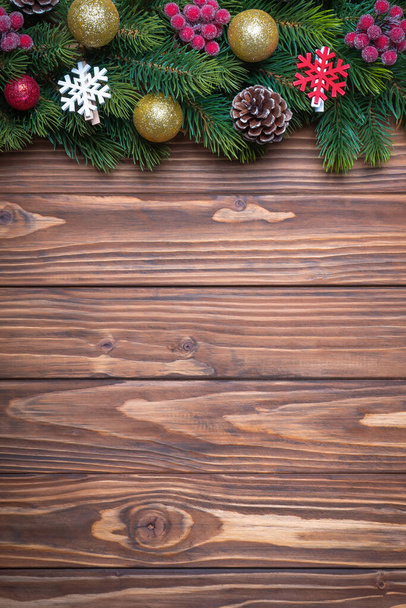 Ramo de árvore de Natal decorado com bolas douradas e verdes, bagas vermelhas e flocos de neve em fundo de madeira marrom. Visão superior, flat lay com espaço de cópia, banner, cabeçalho, fundo de Ano Novo - Foto, Imagem